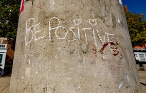 White chalk on concrete pillar with text reading "Be Positive"